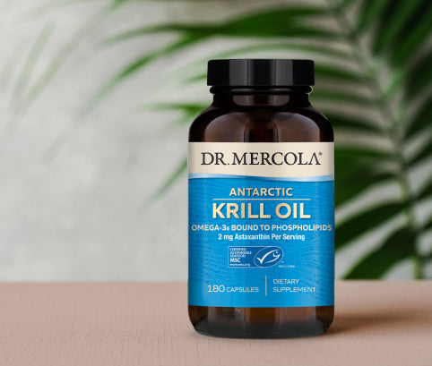 Dr. Mercola Antarctic Krill Oil, omega-3s bound to phospholipids, 180 capsules, in front of a palm leaf.